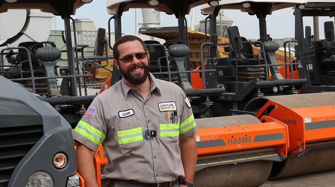 Field Service Tech standing in front of HAMM roller machines smiling
